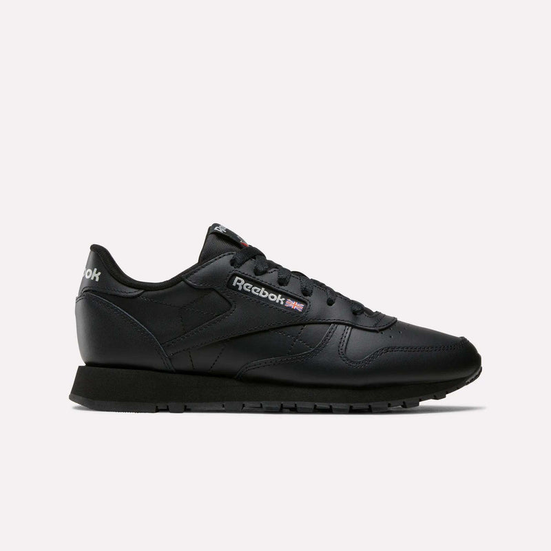 The Women's Classic Leather Shoes by Reebok, in black with a low-cut design, cushioned midsole, black sole, and side Reebok logo with UK flag, are shown against a plain white background.