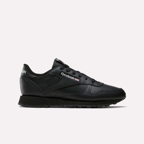 The Reebok Women's Classic Leather Shoes feature a low-top design with black laces and a black sole. Seen from the side on a white background, the Reebok logo highlights this stylish pair of women's shoes.
