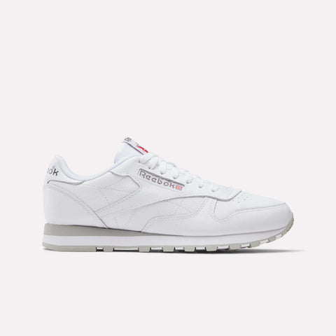 The Reebok Classic Leather Shoes feature a white leather upper, grey outsole, and subtle silver and red branding, shown in a side profile on a white background for a timeless retro look.