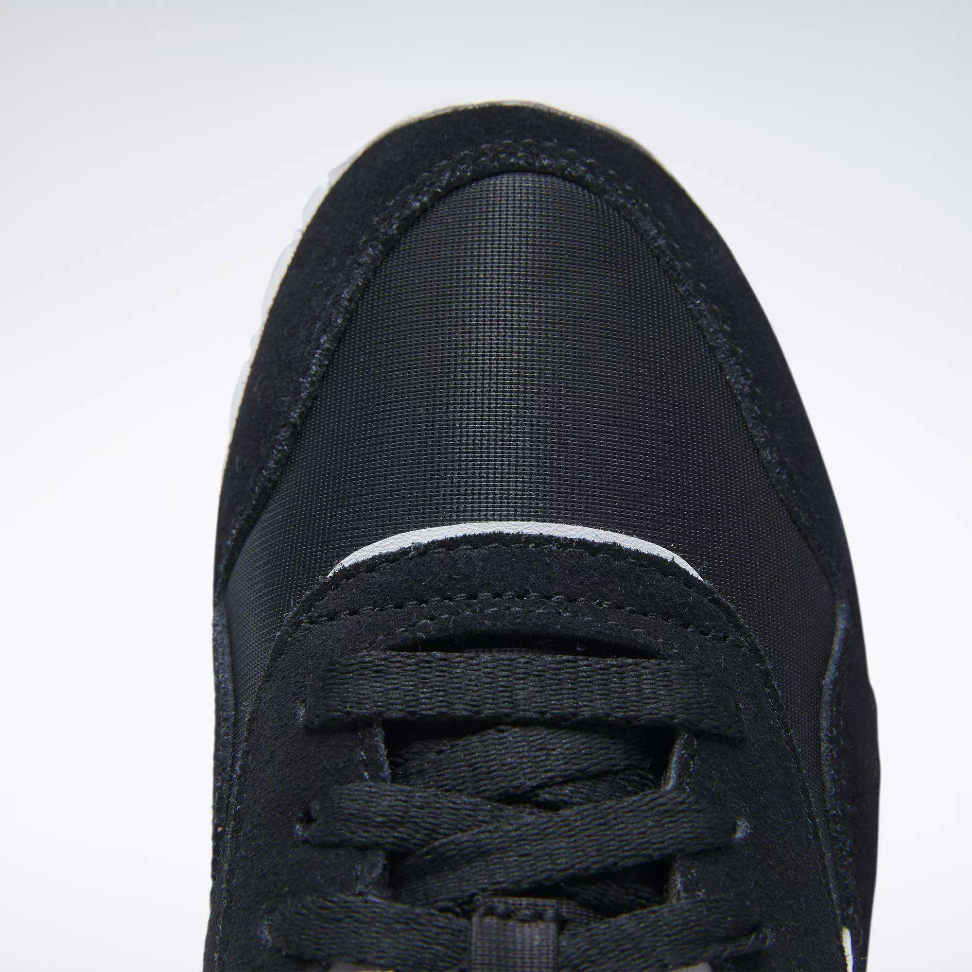 Close-up top view of the front of a black Reebok Women's Classic Nylon Shoe with black laces and a textured, rounded toe cap, shown against a plain white background.