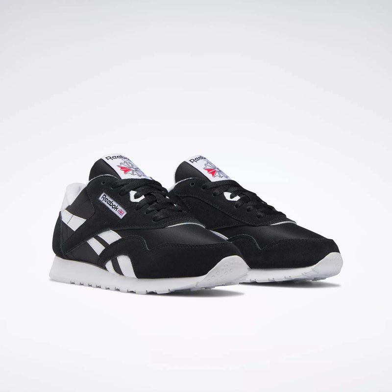 A pair of Women's Classic Nylon Shoes by Reebok in black suede with white soles, side stripes, and tongue labels showing the Reebok logo and Union Jack, ideal as everyday sneakers and shown on a plain white background.