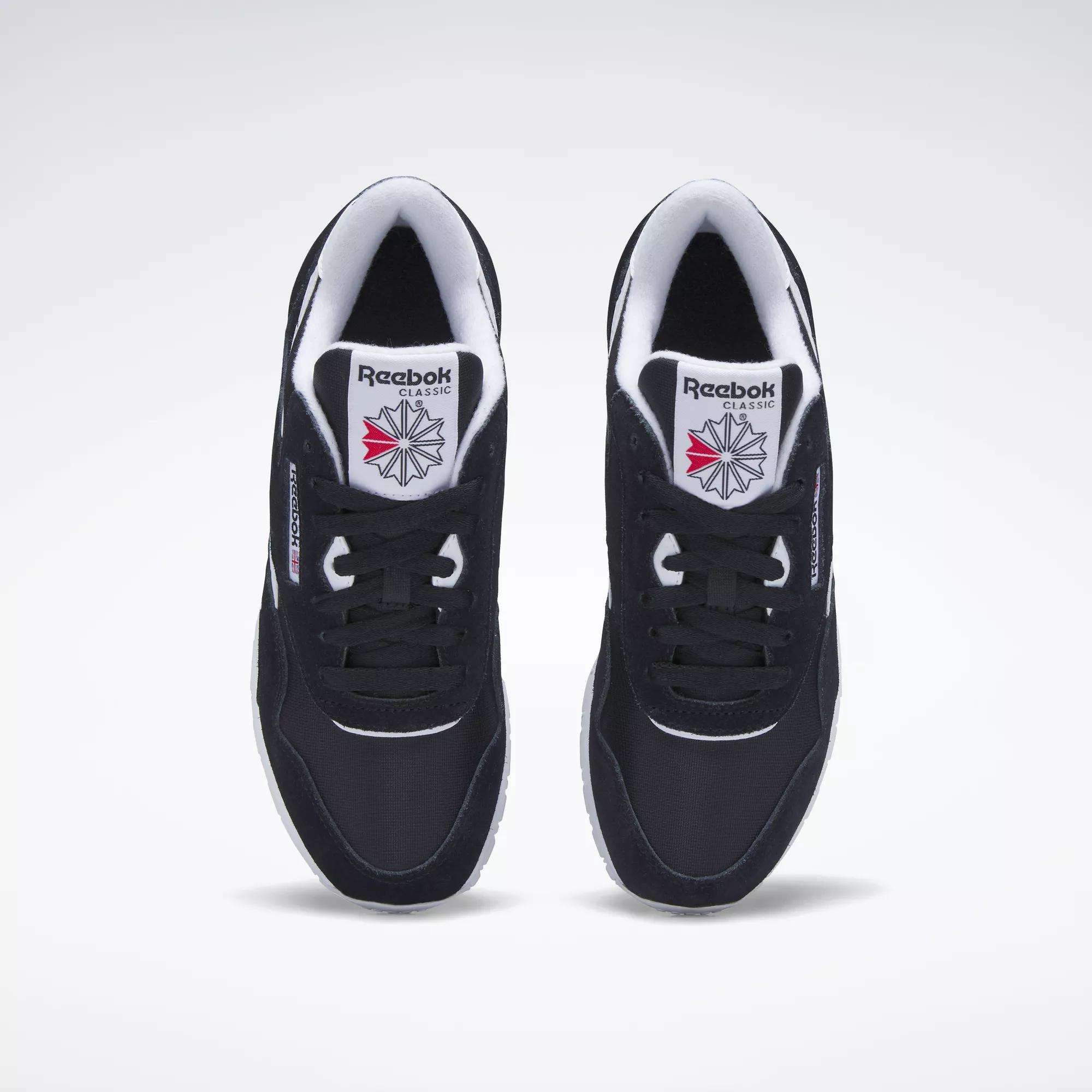 A top view of black Reebok Women's Classic Nylon Shoes with white soles and inner lining, featuring the Reebok logo and a red-and-grey starburst design on the tongue.