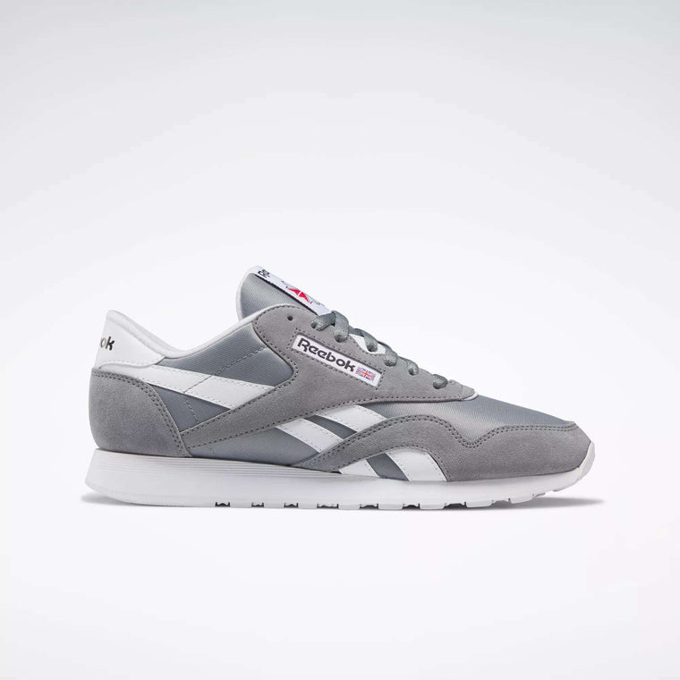 The Reebok Men's Classic Nylon Shoes are shown in grey and white in a side profile on a white background. With a nylon upper and signature side stripes, these timeless sneakers are perfect for everyday wear.