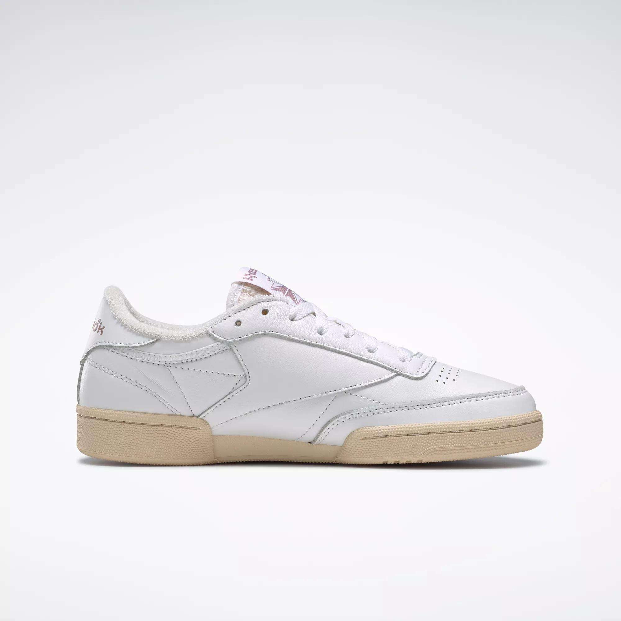 The Reebok Women's Club C 85 Vintage Shoes are white leather sneakers with a beige rubber sole, subtle stitching, and a low-cut design. Shown in side profile on a plain white background.