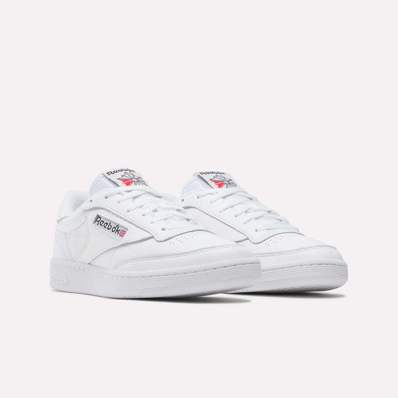 A pair of Reebok Club C 85 Shoes featuring low tops, white soles, and blue and red logos on the side and tongue, shown against a plain white background.