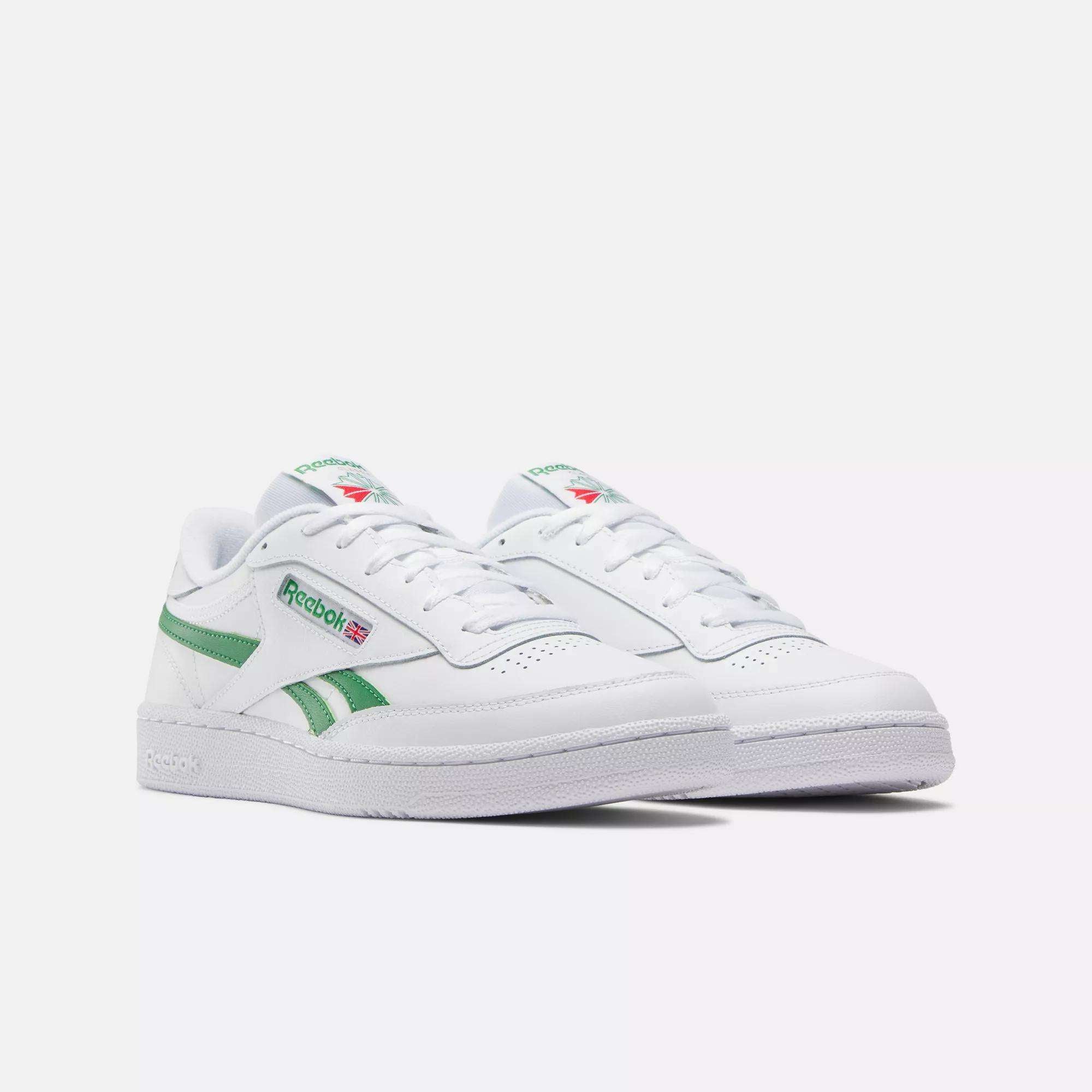 A pair of Reebok Club C Revenge Shoes in white with green accents and the Reebok logo and flag on the side, shown against a plain white background.