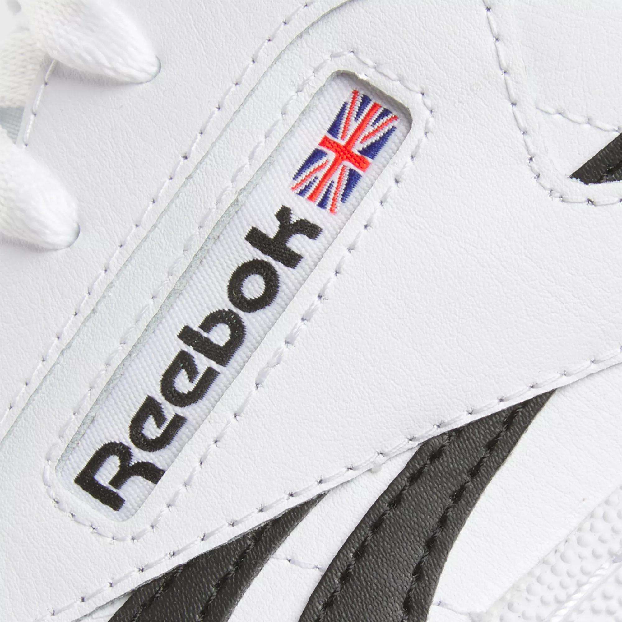 Close-up of the Reebok Club C Revenge Shoes in white, featuring the black Reebok logo and a small Union Jack flag on the side, with contrasting black and white design accents.