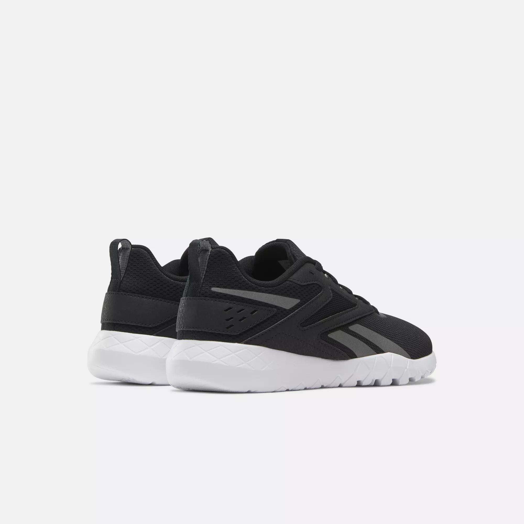 A pair of Reebok Women's Flexagon Energy 4 Training Shoes in black with white soles are displayed on a plain light background, angled to showcase their textured modern design and responsive cushioning.