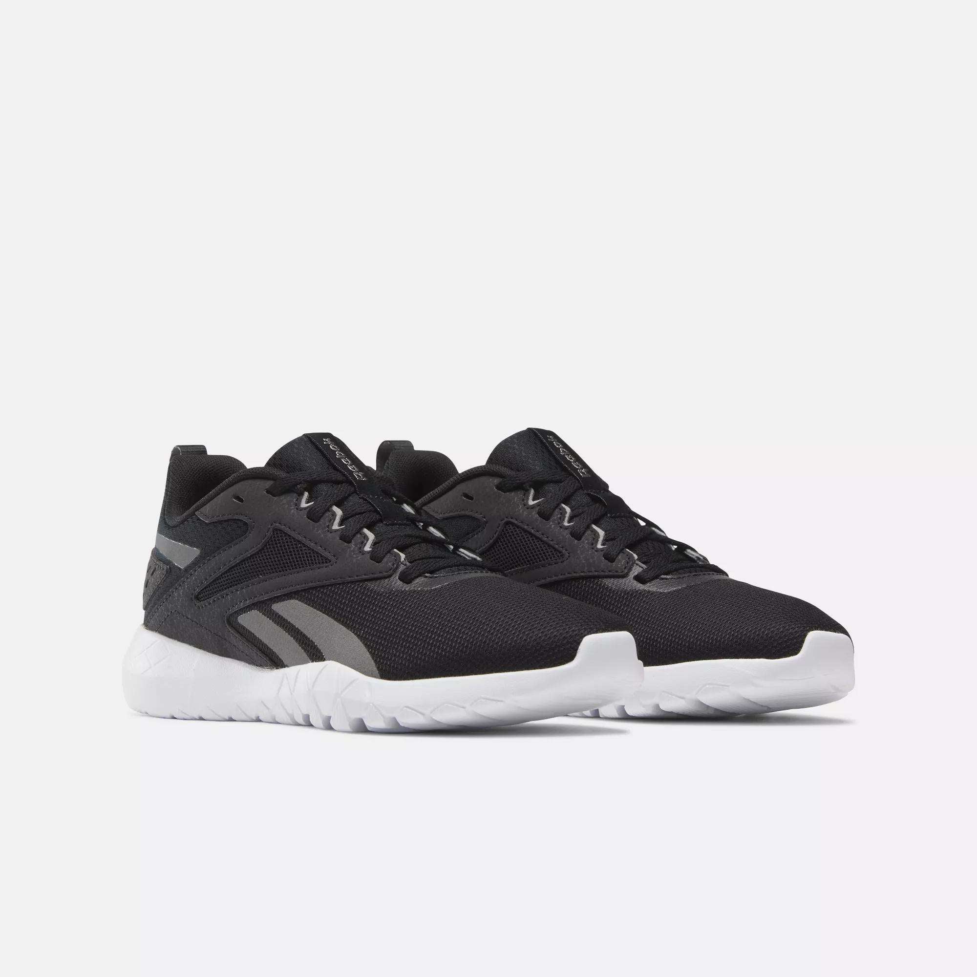 A pair of Reebok Women's Flexagon Energy 4 Training Shoes in black with white soles and gray accents, featuring a lightweight build and responsive cushioning, are shown side by side on a plain light background.