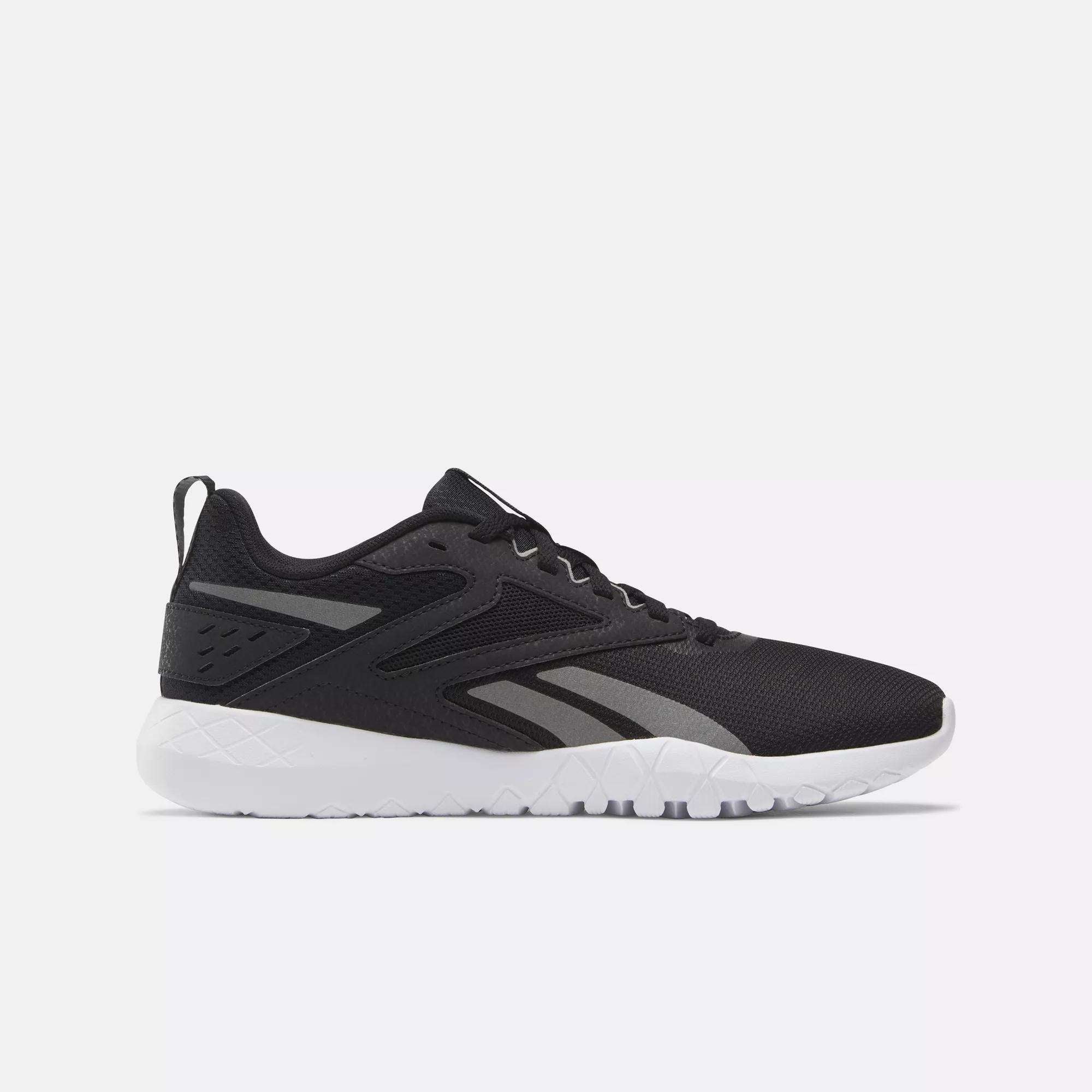 The Reebok Women's Flexagon Energy 4 Training Shoe, shown in side profile on a light background, features a black upper with gray accents, a white sole, and responsive cushioning for comfort.