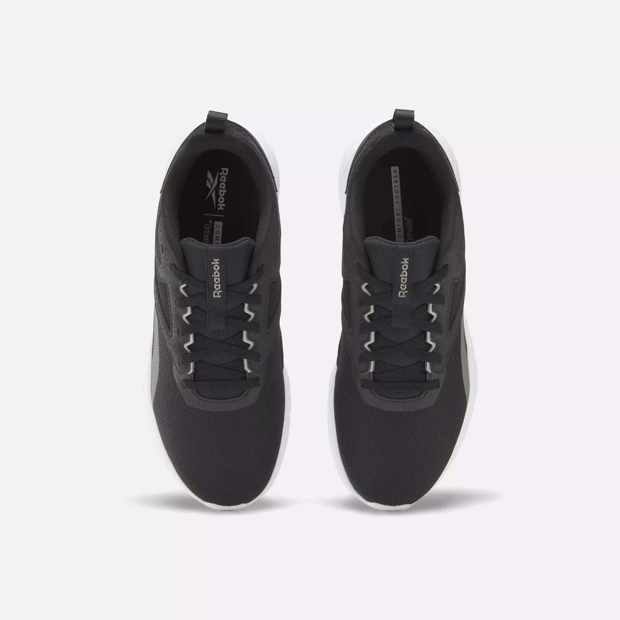 A top-down view of Reebok Women's Flexagon Energy 4 Training Shoes in black with white soles and laces, featuring responsive cushioning, displayed side by side on a light background.