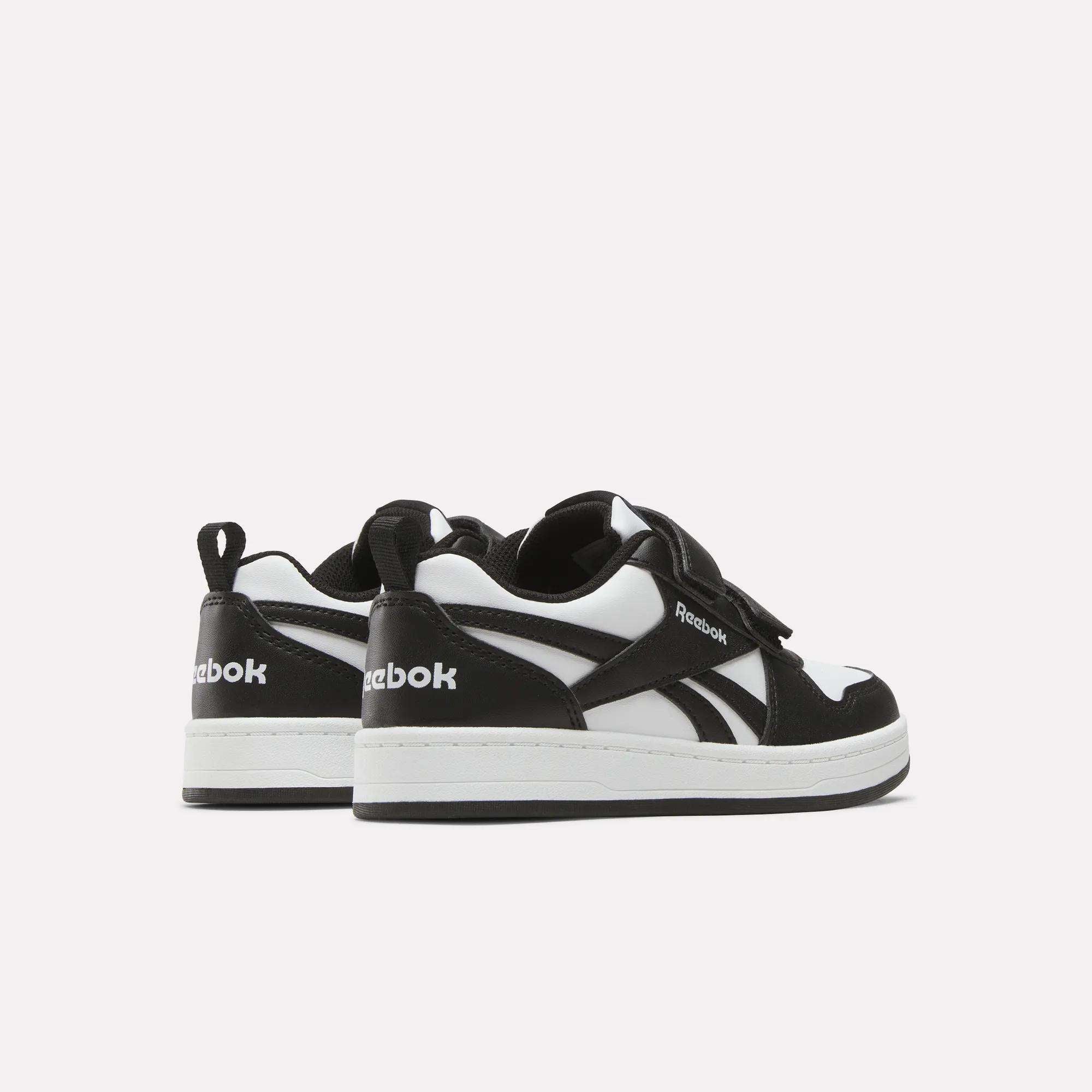Kids' Reebok Royal Prime 2 Shoes by Reebok in black and white, featuring white soles, hook-and-loop straps, and the Reebok logo on the side and heel, shown against a plain light background.