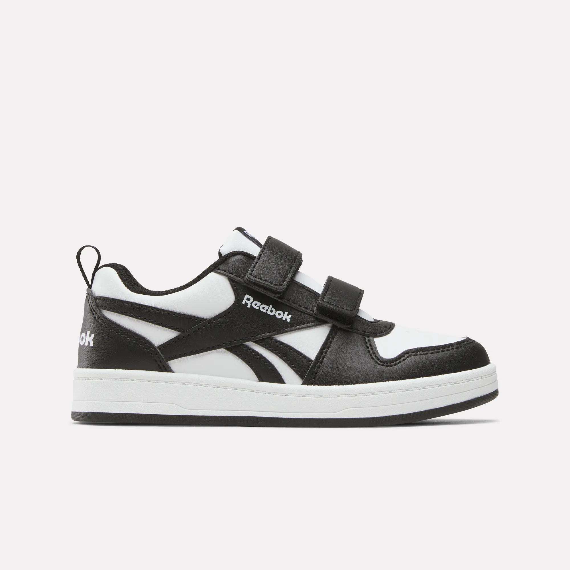 The Kids' Reebok Royal Prime 2 Shoes by Reebok are black and white sneakers featuring two hook-and-loop straps, a white sole, and the Reebok logo on the side, shown against a plain light background.