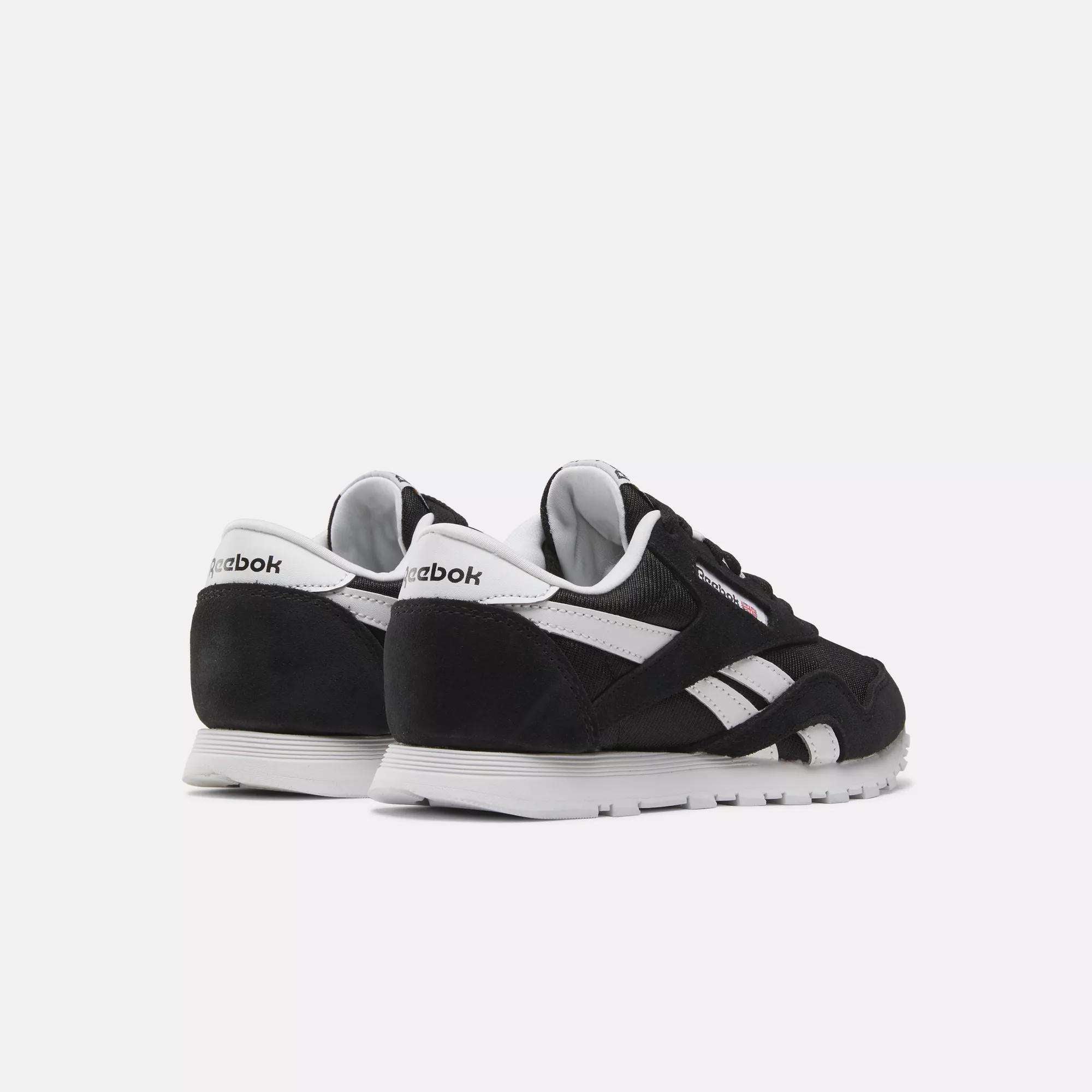 The Reebok Kids' Classic Nylon Shoes - Preschool feature a black design with white soles and accents, including the Reebok logo on the heel and side, offering lightweight cushioning for all-day comfort, shown against a plain white background.