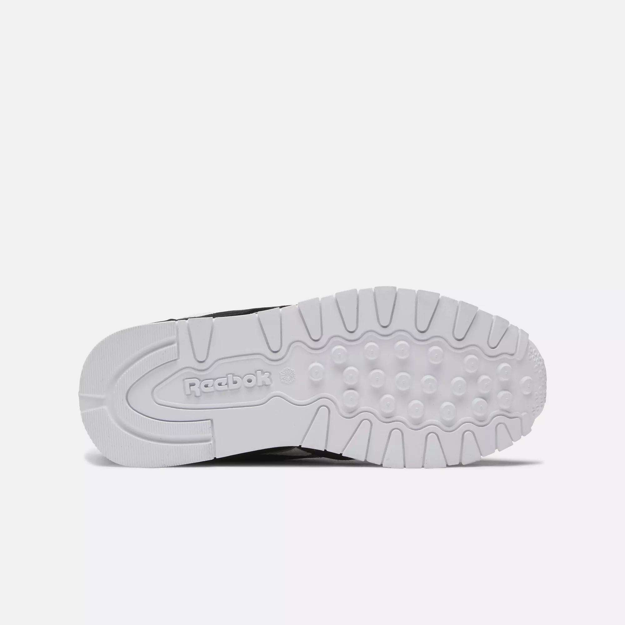 The image displays the white sole of Reebok Kids' Classic Nylon Shoes - Preschool, viewed from beneath. The sole has textured grip patterns, circular treads, and an embossed Reebok logo near the heel for style and cushioning.
