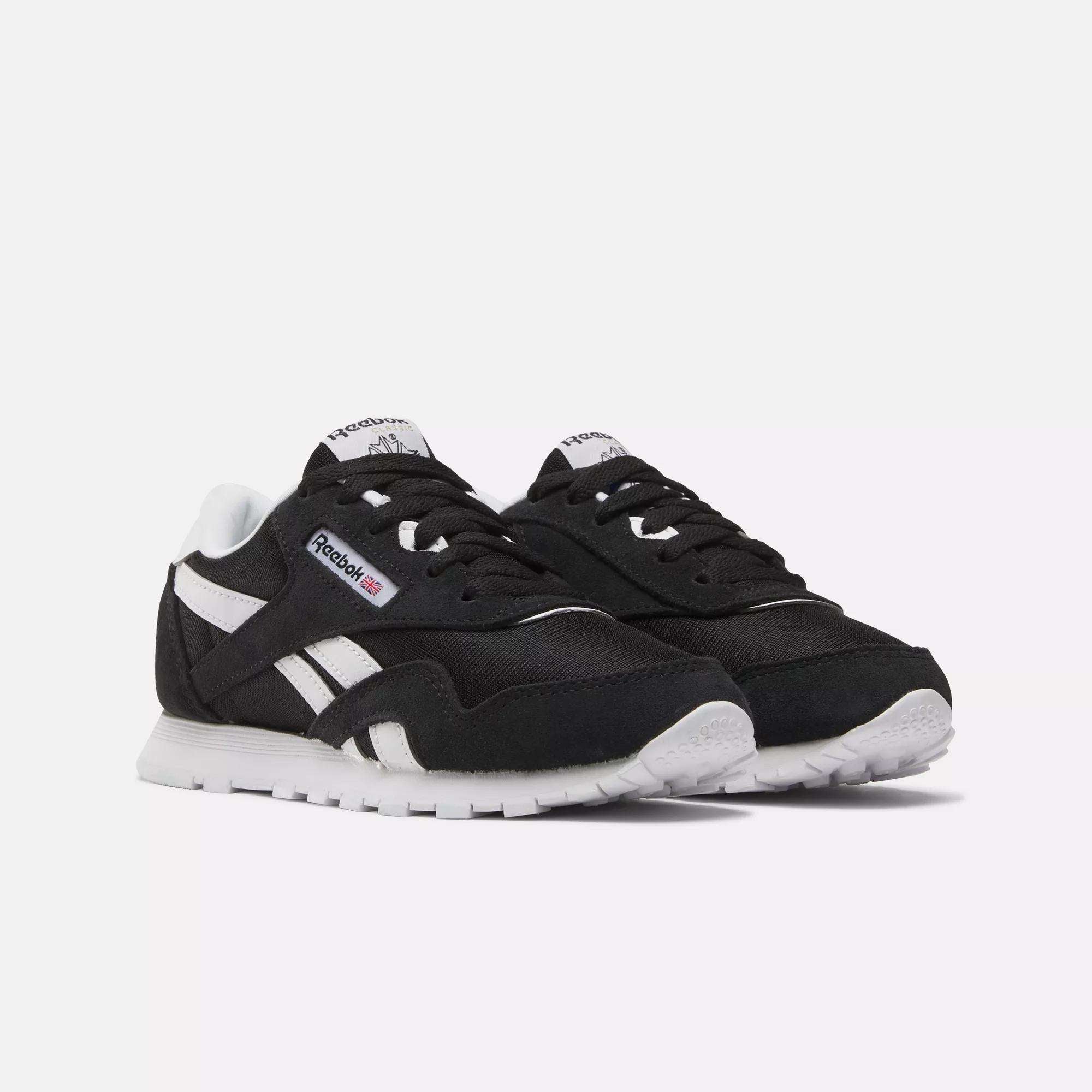 A pair of black Reebok Kids' Classic Nylon Shoes - Preschool with white soles, white side stripes, and the Reebok logo on the side and tongue, featuring lightweight cushioning, displayed on a plain white background.