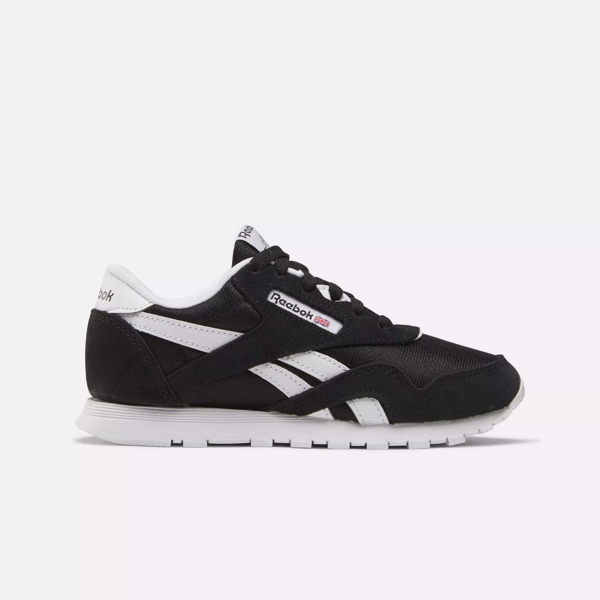 Side view of Kids' Classic Nylon Shoes - Preschool by Reebok in black with white accents, iconic logo, and stripes. Designed for boys, these sneakers offer lightweight cushioning, a white sole, and black laces on a light background.