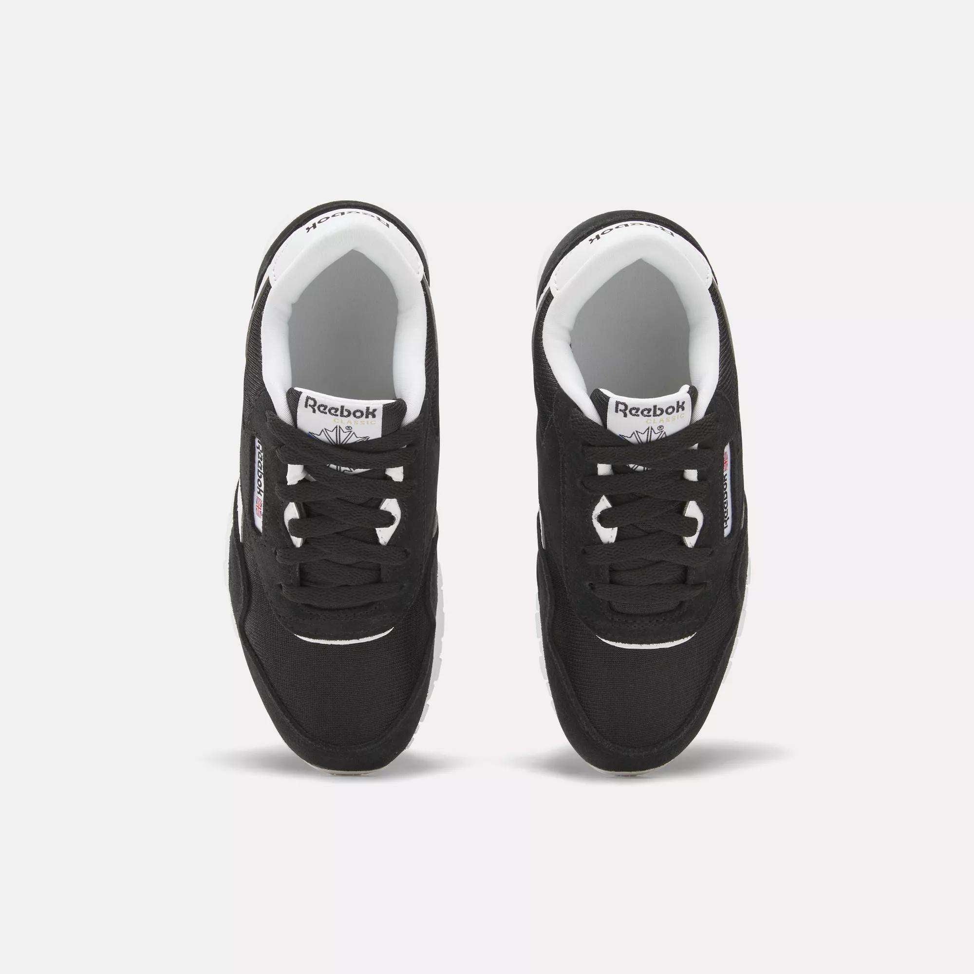 A pair of black Reebok Kids' Classic Nylon Shoes – Preschool, with white soles and inner lining, seen from above on a white background. The sneakers feature the Reebok logo on the tongue and side and provide lightweight cushioning for comfort.