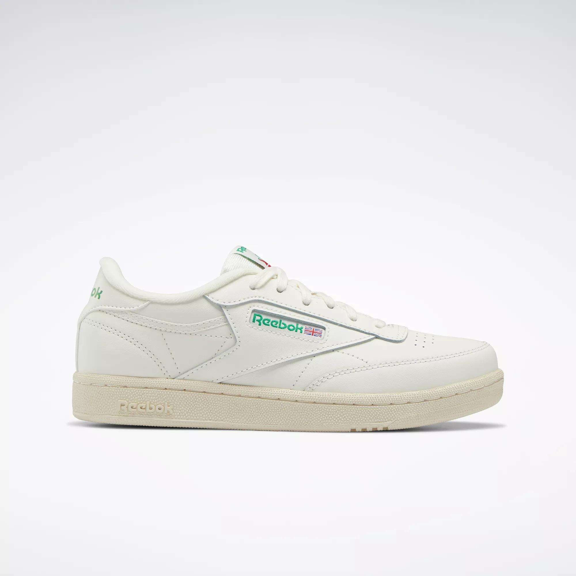 The Reebok Club C Shoes - Big Kids feature a white upper, green and red logo accents, beige sole, and classic low-top '80s style. Shown in profile on a light background, they're perfect for junior boys wanting timeless Reebok sneakers.