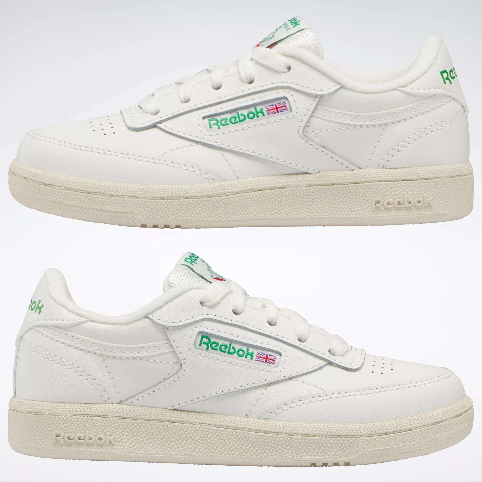 Two white Reebok Kids' Club C Shoes - Preschool, shown from the side with green and red logo details and an off-white sole, bring timeless '80s style for everyday wear.