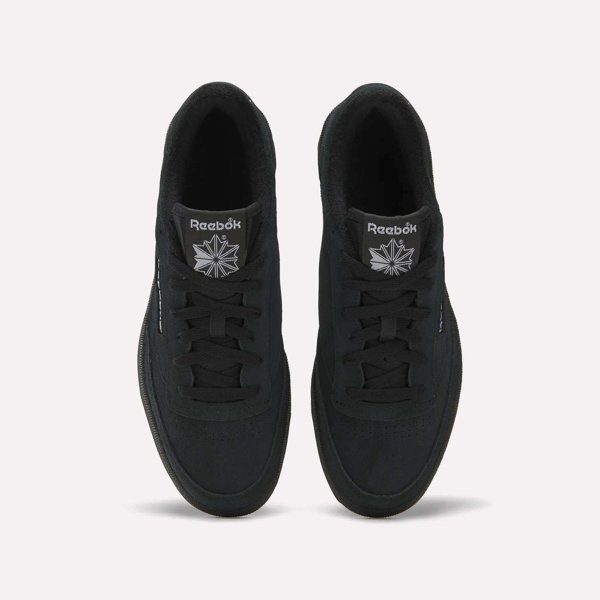 Top view of Reebok Club C 85 Shoes in black with a suede upper, black laces, and soles. The white Reebok logo is visible on the tongue, set against a plain light background.