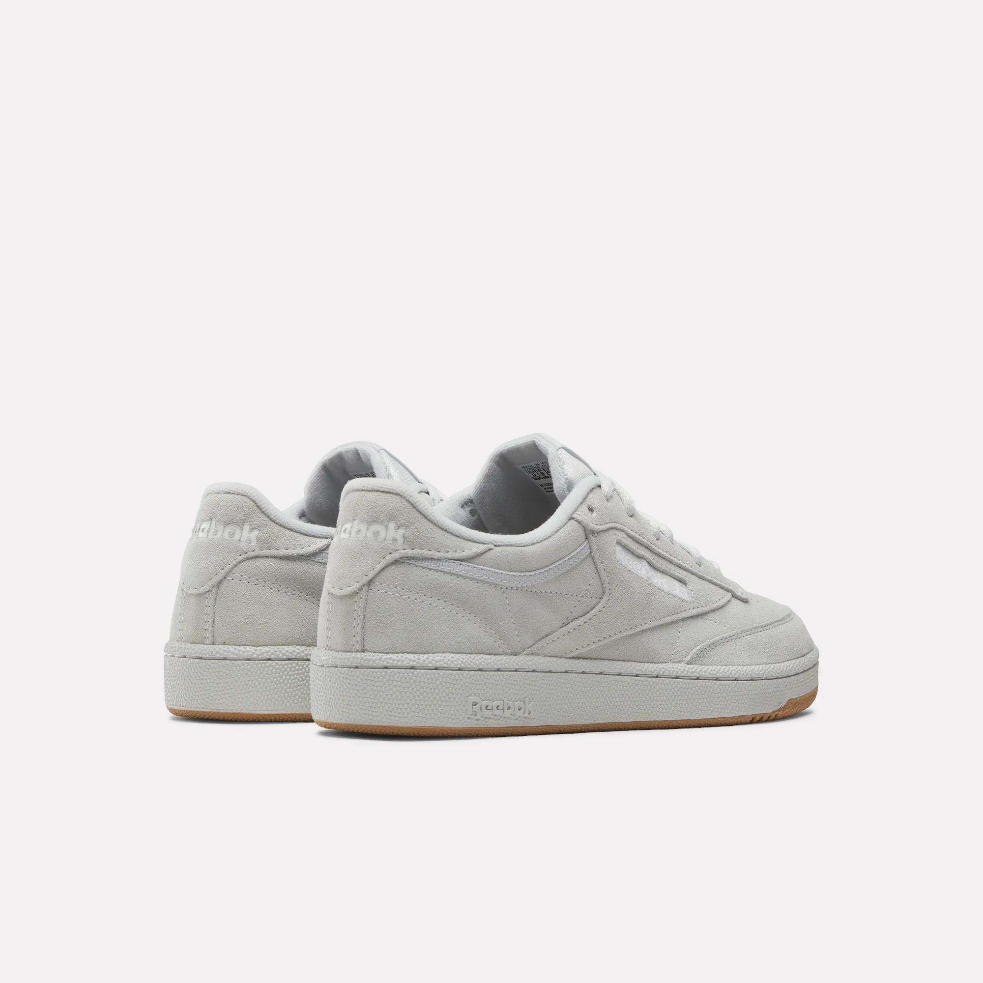 The Reebok Club C 85 Shoes feature a light gray suede upper, white laces, and beige rubber soles, displayed from an angled back and side view against a plain white background.