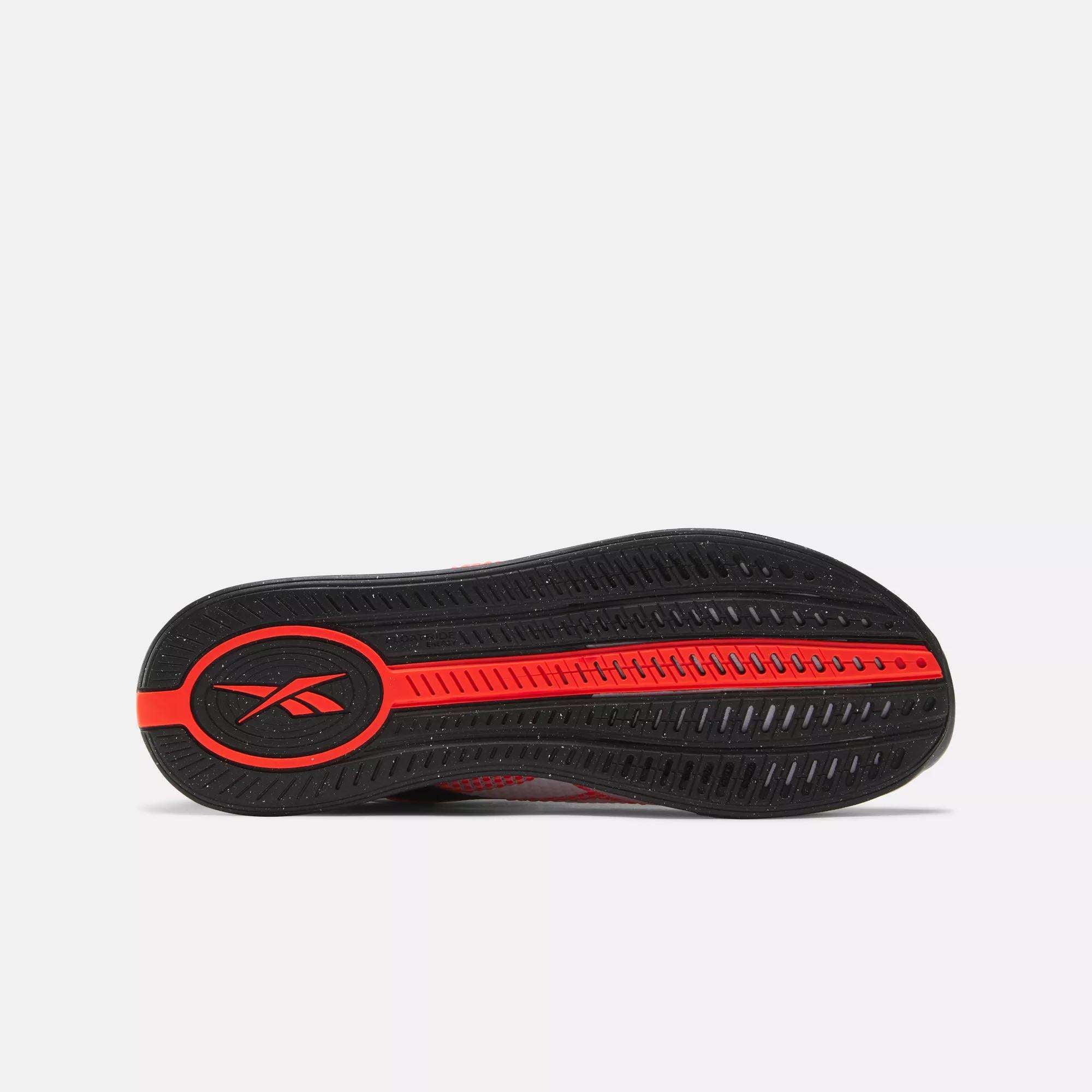 Bottom view of the Reebok Nano X4 Training Shoes in black and red, showing a lightweight, breathable sole with grooves and patterns for traction and the Reebok logo in a circular section at the heel.