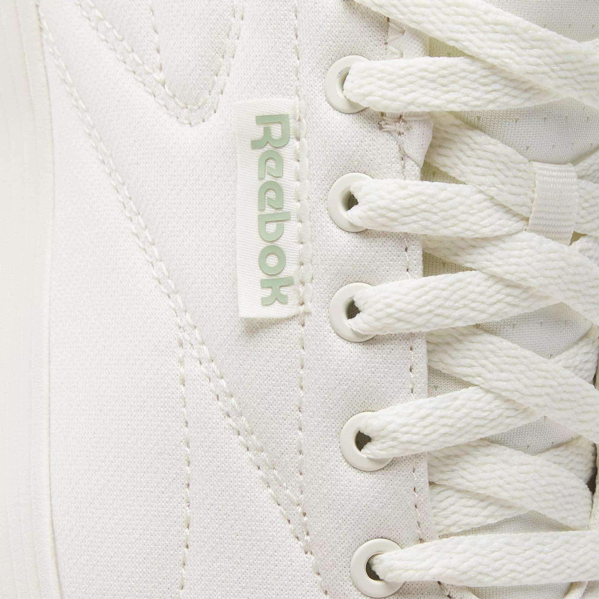 Close-up of Reebok Active Lite Shoes highlighting the iconic logo tag, detailed stitching, and crisp white laces—these minimalist sneakers combine classic design with modern Reebok style.