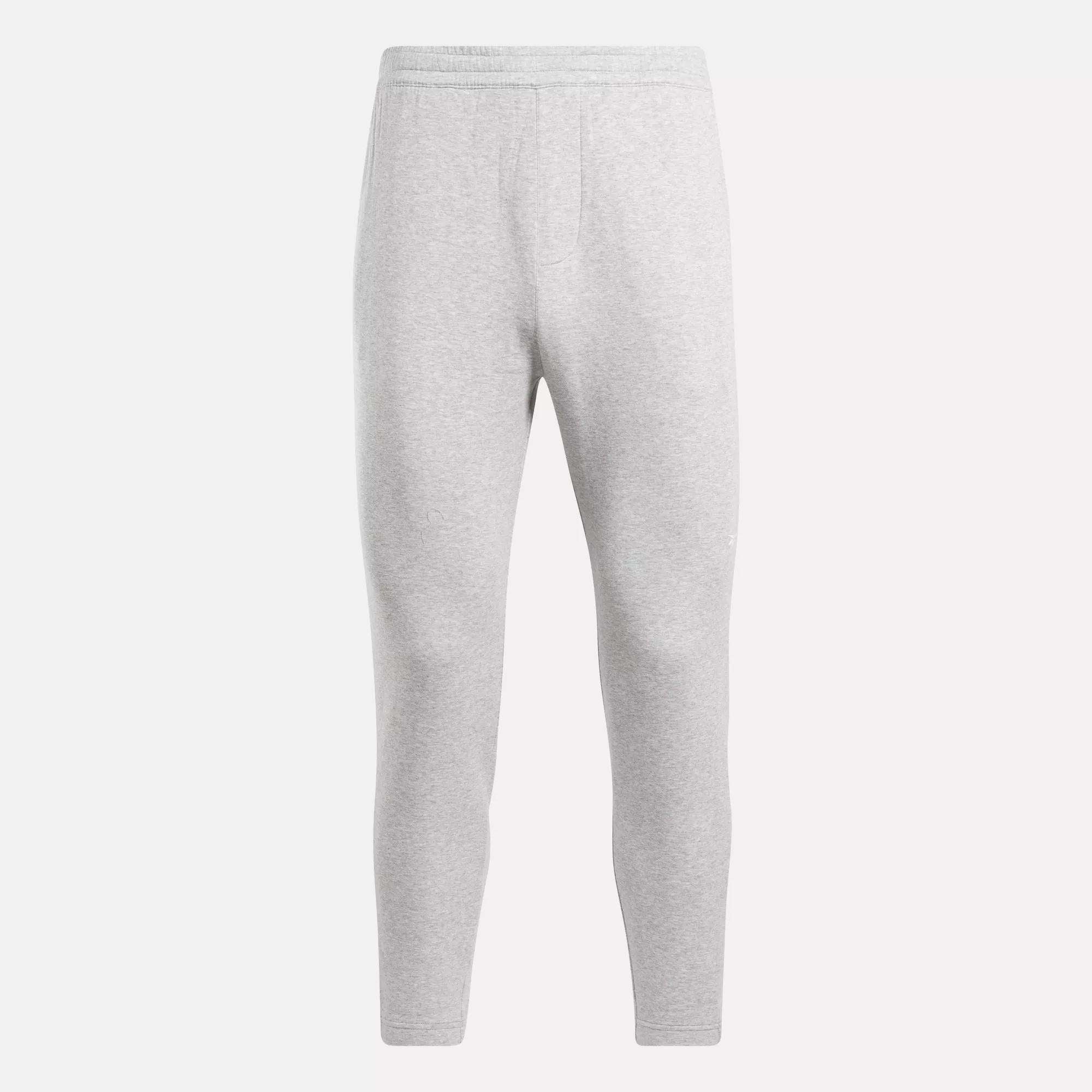The Reebok Men's Active Collective DreamBlend Pants in light gray feature a slim, tapered leg, soft DreamBlend fabric, and an elastic waistband, shown here on a plain white background.
