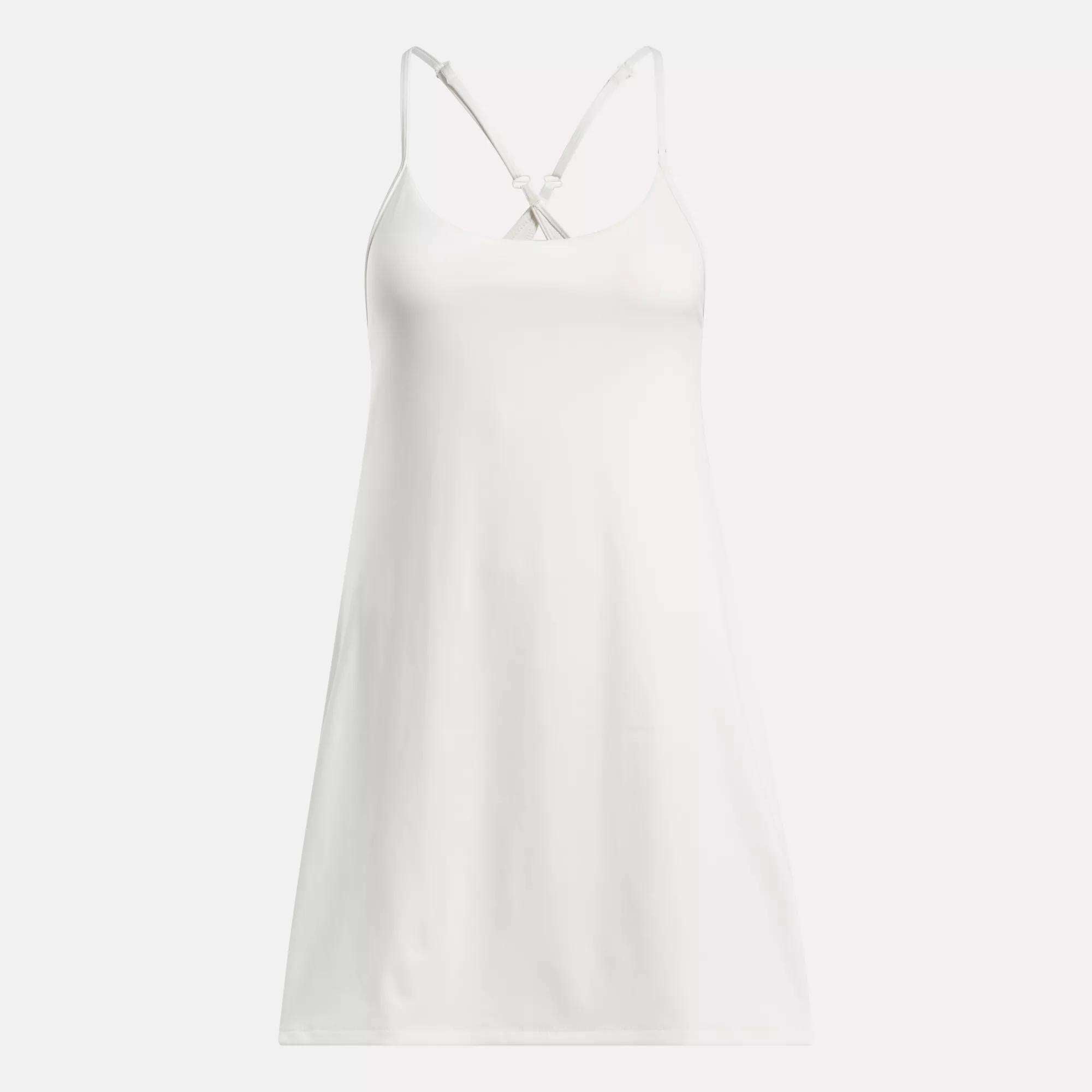 The Reebok Women's Lux Strappy Dress is a sleeveless white slip dress with thin adjustable straps and a V-neckline, designed for comfort and a perfect fit, shown on a plain background.