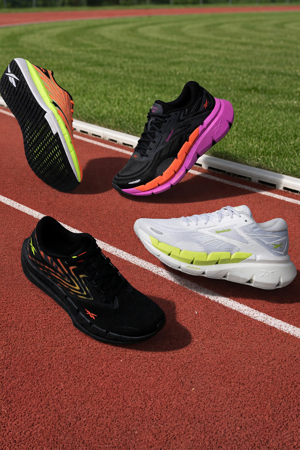Four running shoes on a track with grass in the background