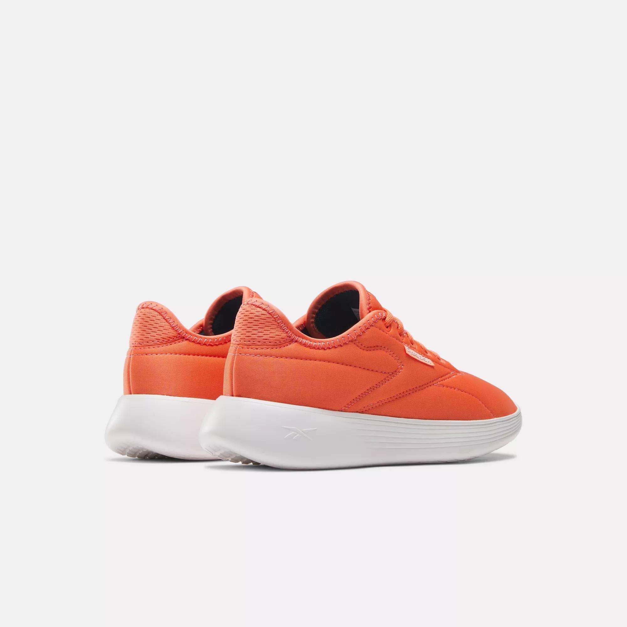 A pair of Women's Active Lite Shoes by Reebok in bright orange with white soles and DMX technology, shown angled on a plain white background.