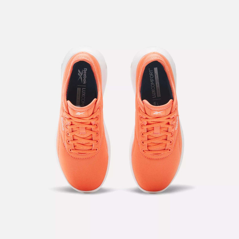 A pair of Women's Active Lite Shoes by Reebok in bright orange with white soles, orange laces, black LUX COMFORT insoles, and DMX technology for all-day support, viewed from above on a plain white background.