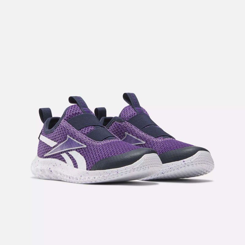 A pair of Reebok Kids' Rush Runner Slip-On Shoes in purple with white soles, black toe caps, lightweight cushioning, and white side logos, displayed on a plain white background.
