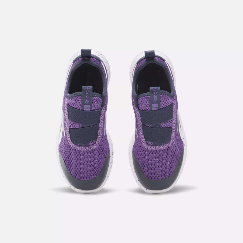 A pair of Reebok Kids' Rush Runner Slip-On Shoes in purple and black, shown from above on a plain background. Mesh uppers, elastic straps, and cushioned soles provide little kids with a secure fit and all-day comfort.