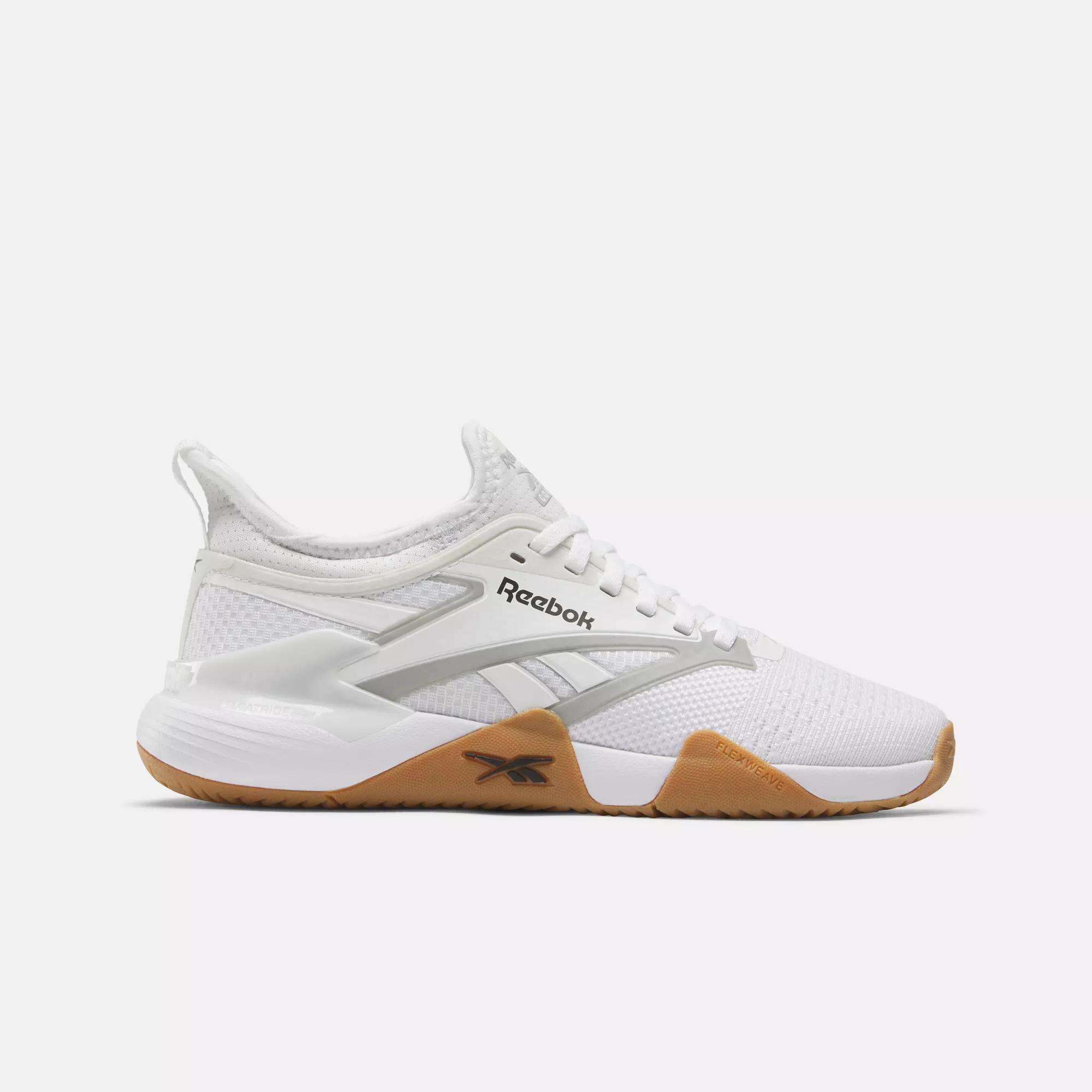 The Reebok Women's Nano Court Training Shoes feature a white mesh upper, white laces, a light brown rubber sole for multidirectional traction, and a modern Reebok logo on the side—ideal for women's training.