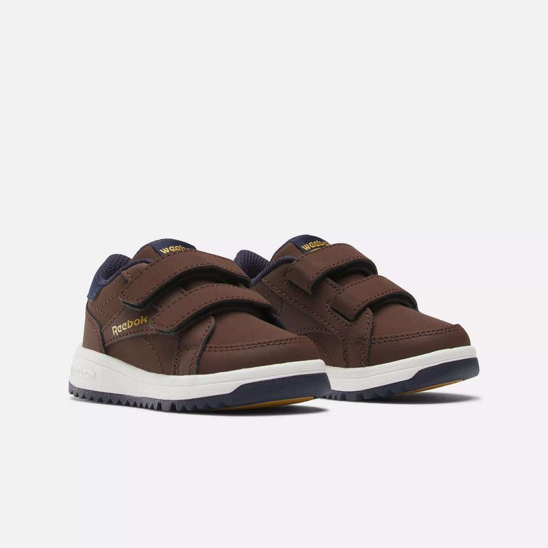 The Reebok Weebok Clasp Low Shoes for infants and toddlers feature brown uppers, navy blue accents, white soles, and two Velcro straps, offering comfort for little ones; shown on a plain white background.