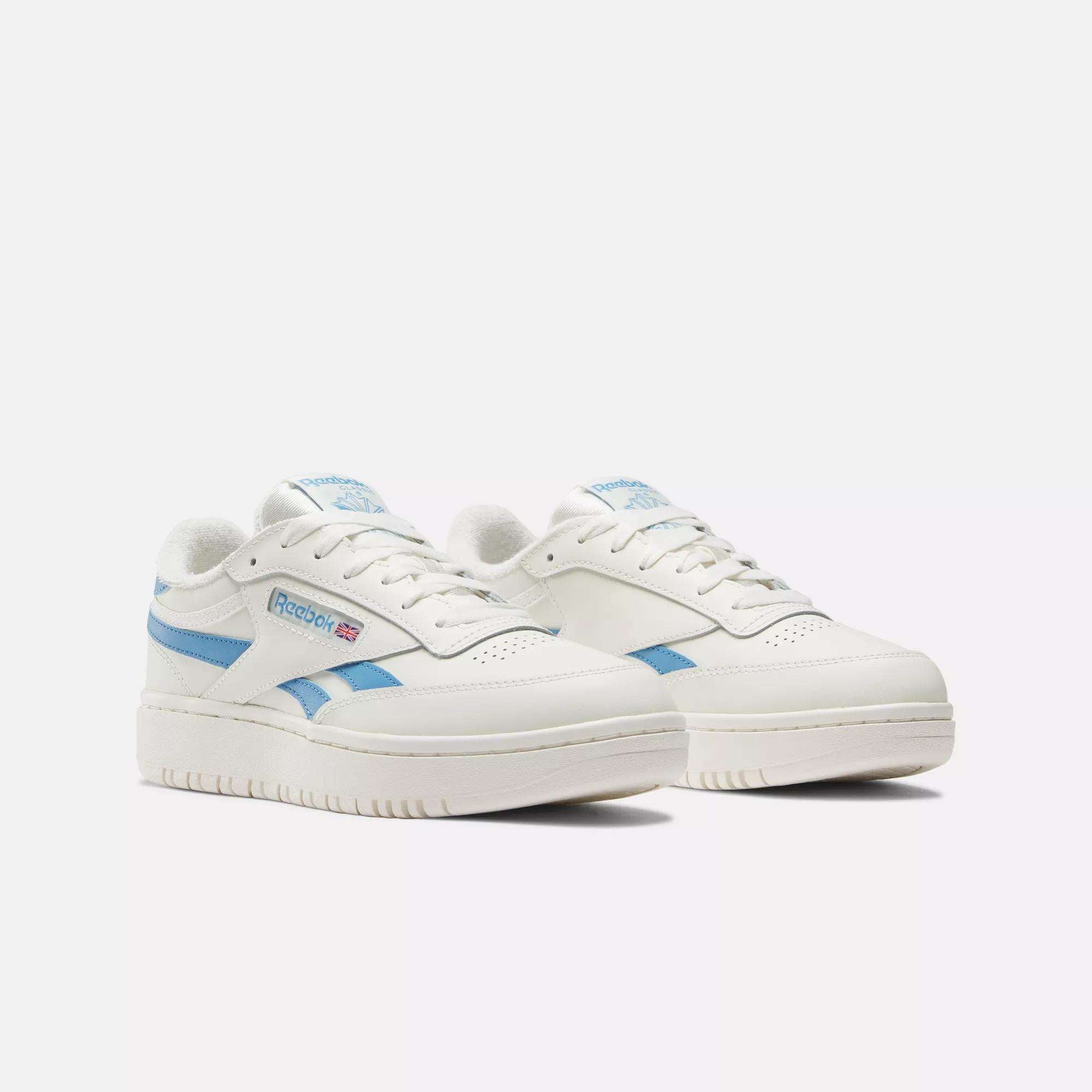 The Women's Club C Double Revenge Shoes by Reebok feature a white leather upper with light blue accents and the Reebok logo on the side. These court-inspired sneakers are shown against a plain white background.