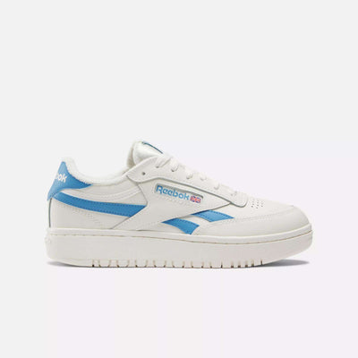 The Women's Club C Double Revenge Shoes by Reebok are white low-top sneakers with light blue accents, a leather upper, Reebok logo and small Union Jack flag on the side, white laces, and a textured rubber court-inspired sole.