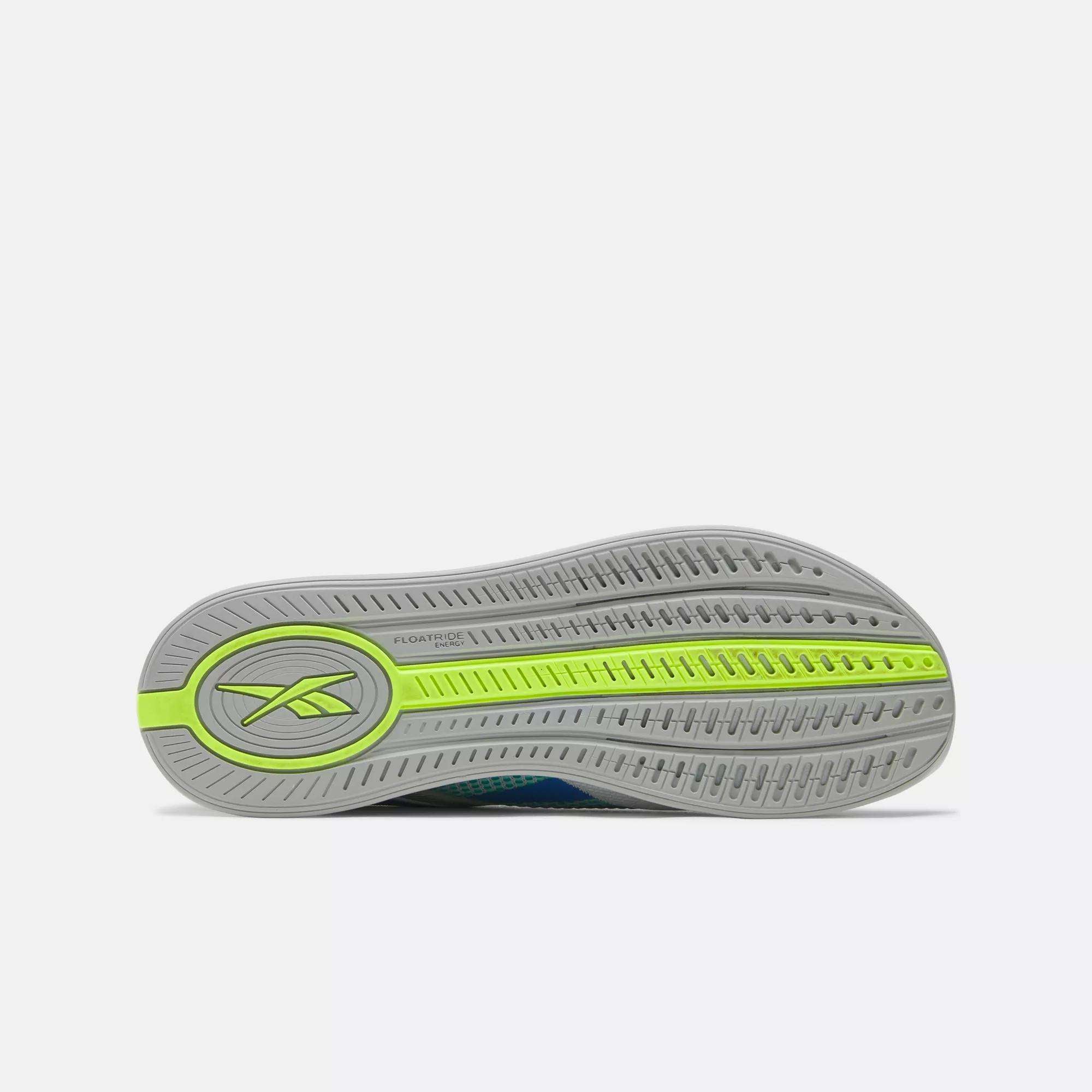 The image displays the sole of Reebok Nano X4 Training Shoes, featuring a lightweight gray base with textured grooves for grip, a green stripe, and the Reebok logo near the heel.