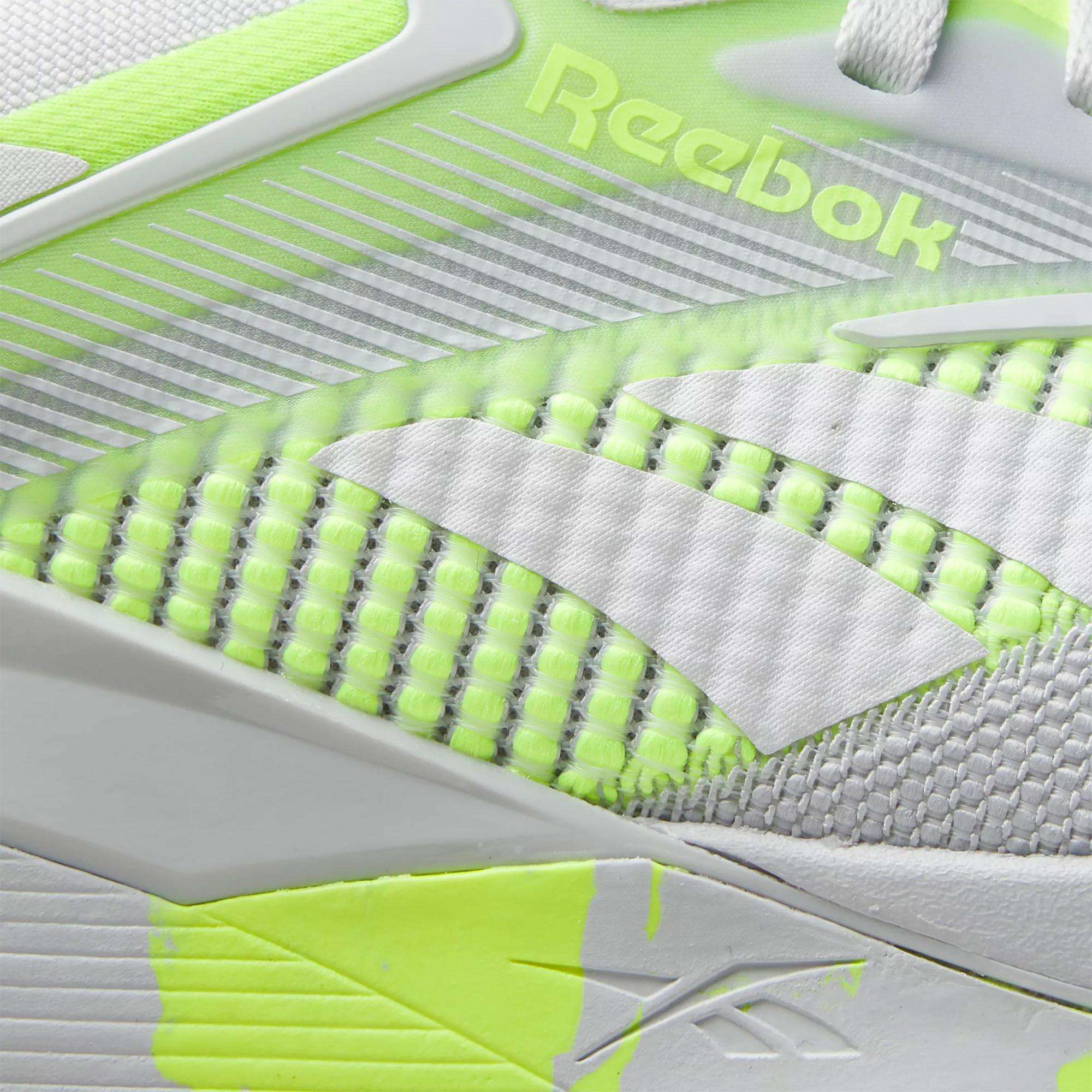 Close-up of Reebok Nano X4 Training Shoes, featuring a white and neon yellow design with breathable mesh and the Reebok logo by geometric accents—lightweight and perfect for training.