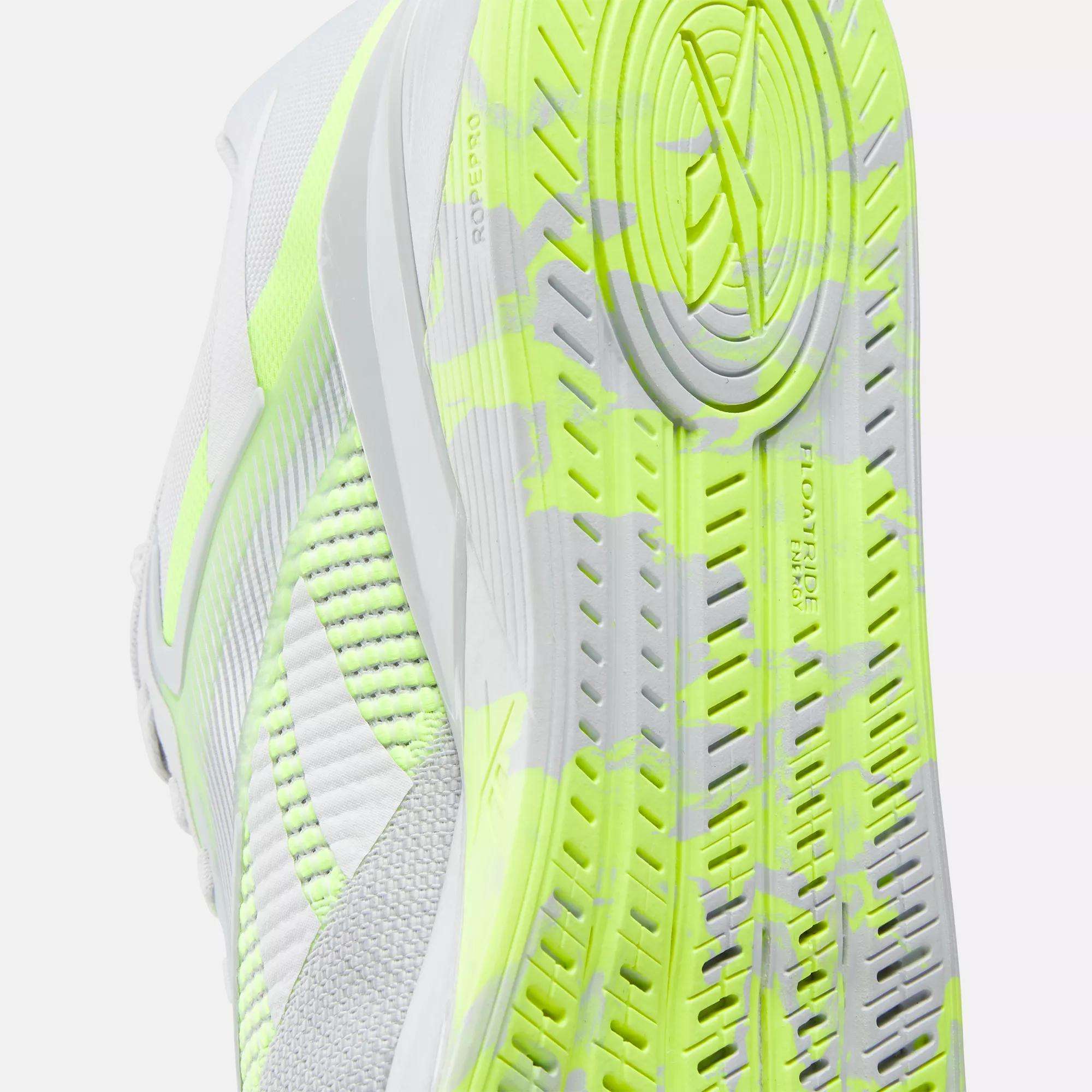 Close-up of the Reebok Nano X4 Training Shoe’s sole in white with neon yellow and gray accents, highlighting its detailed tread pattern and textured design.