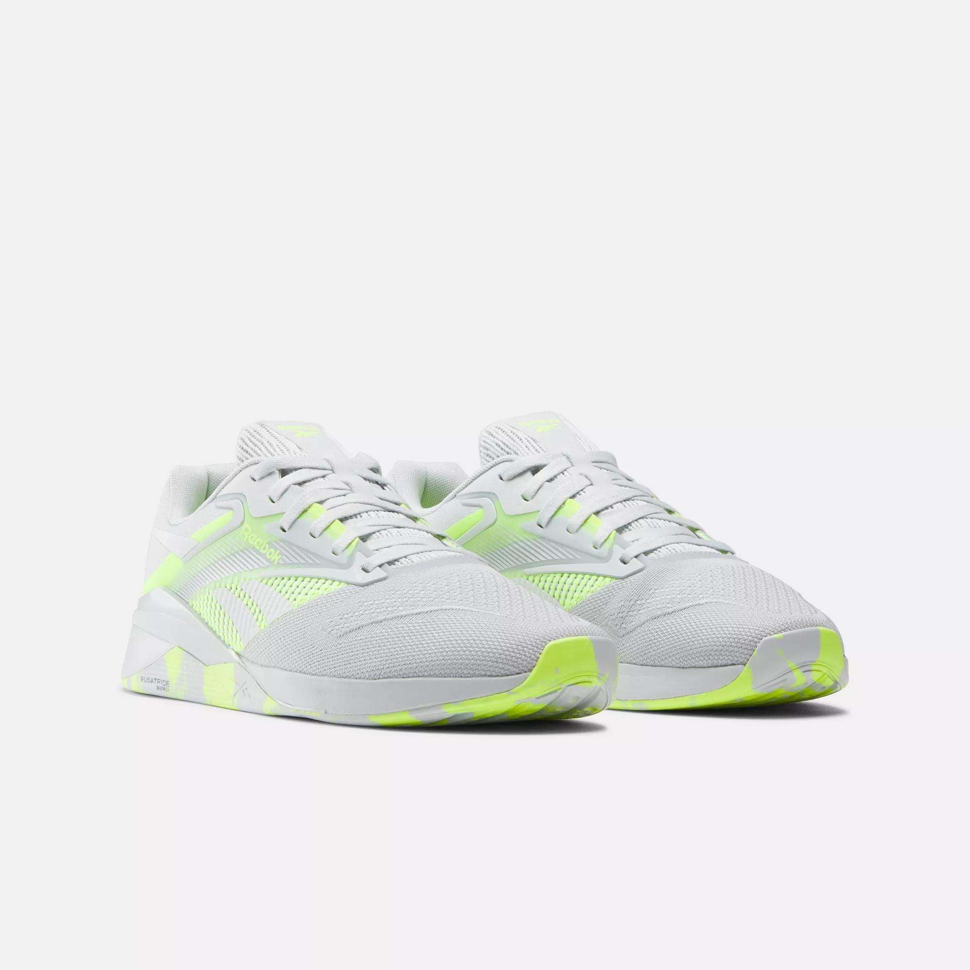 A pair of Reebok Nano X4 Training Shoes in white with neon yellow accents on the sides, tongue, heel, and outsole, displayed on a plain light background.