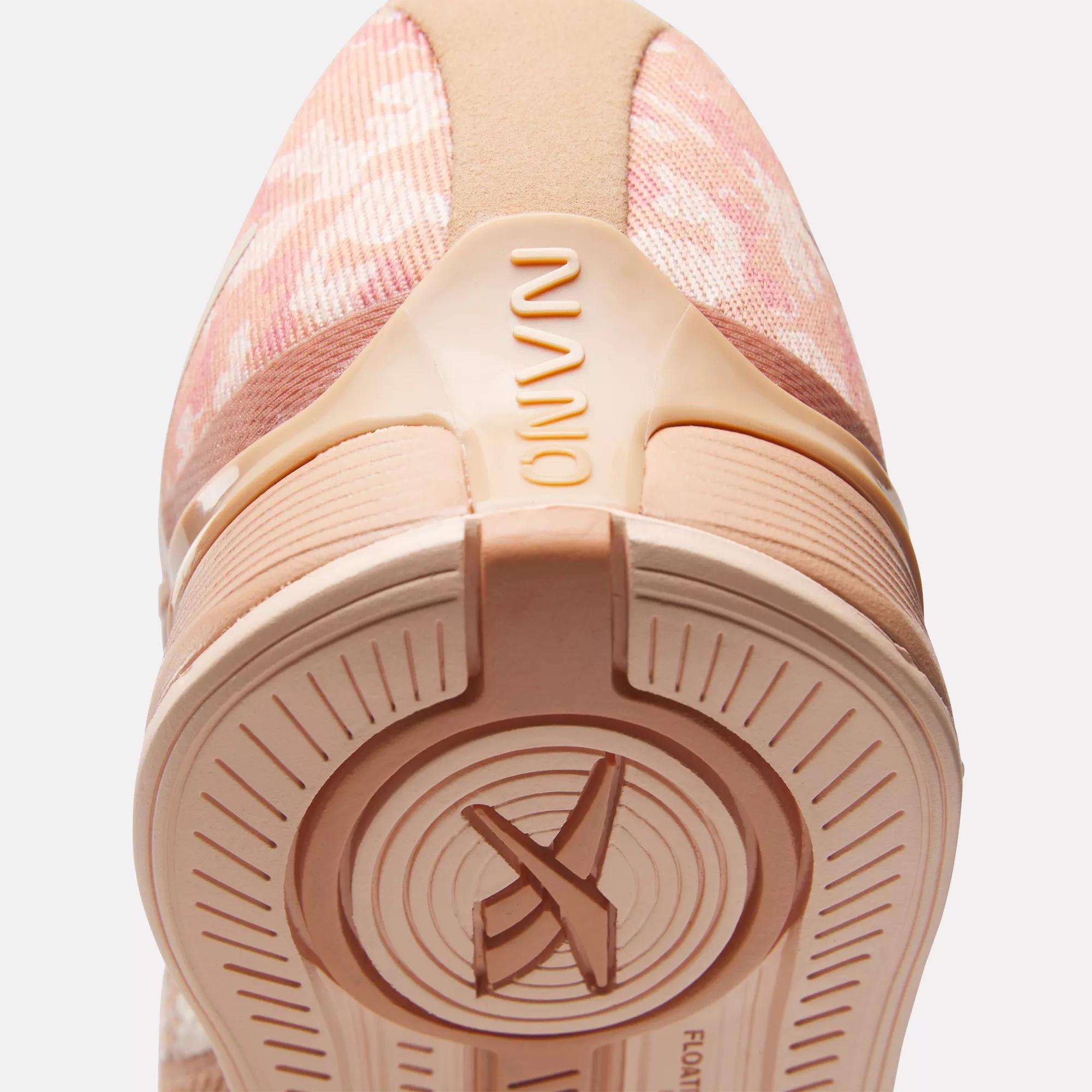 Close-up of the heel and sole of Reebok Women's Nano X4 Training Shoes in pink with beige accents. "NANO" appears on the heel, and the lightweight, breathable sole features circular patterns with an X design at the center.