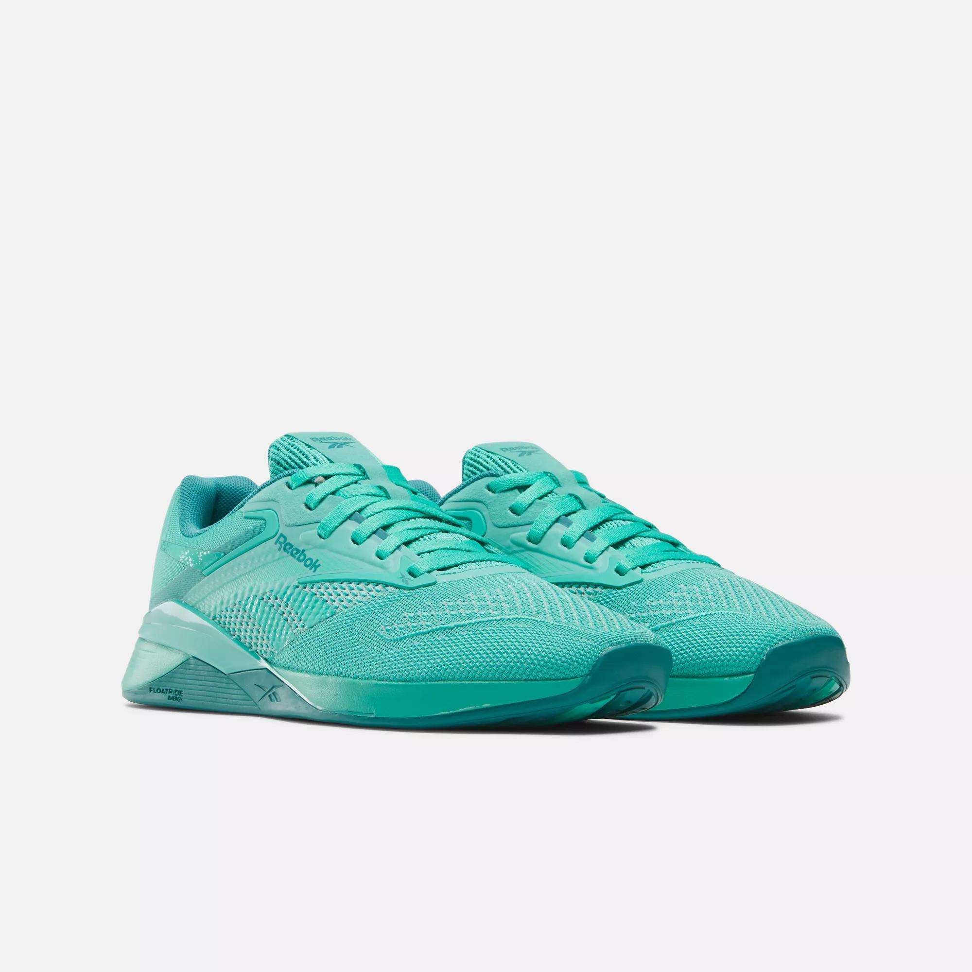 A pair of Reebok Women's Nano X4 Training Shoes in teal, featuring mesh uppers, flat laces, and rubber soles, are displayed side by side on a white background.