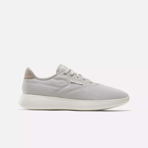 The Reebok Active Lite Shoes feature a light gray, minimalist low-top design with white laces, a textured off-white sole, and a beige heel accent, displayed against a plain white background.
