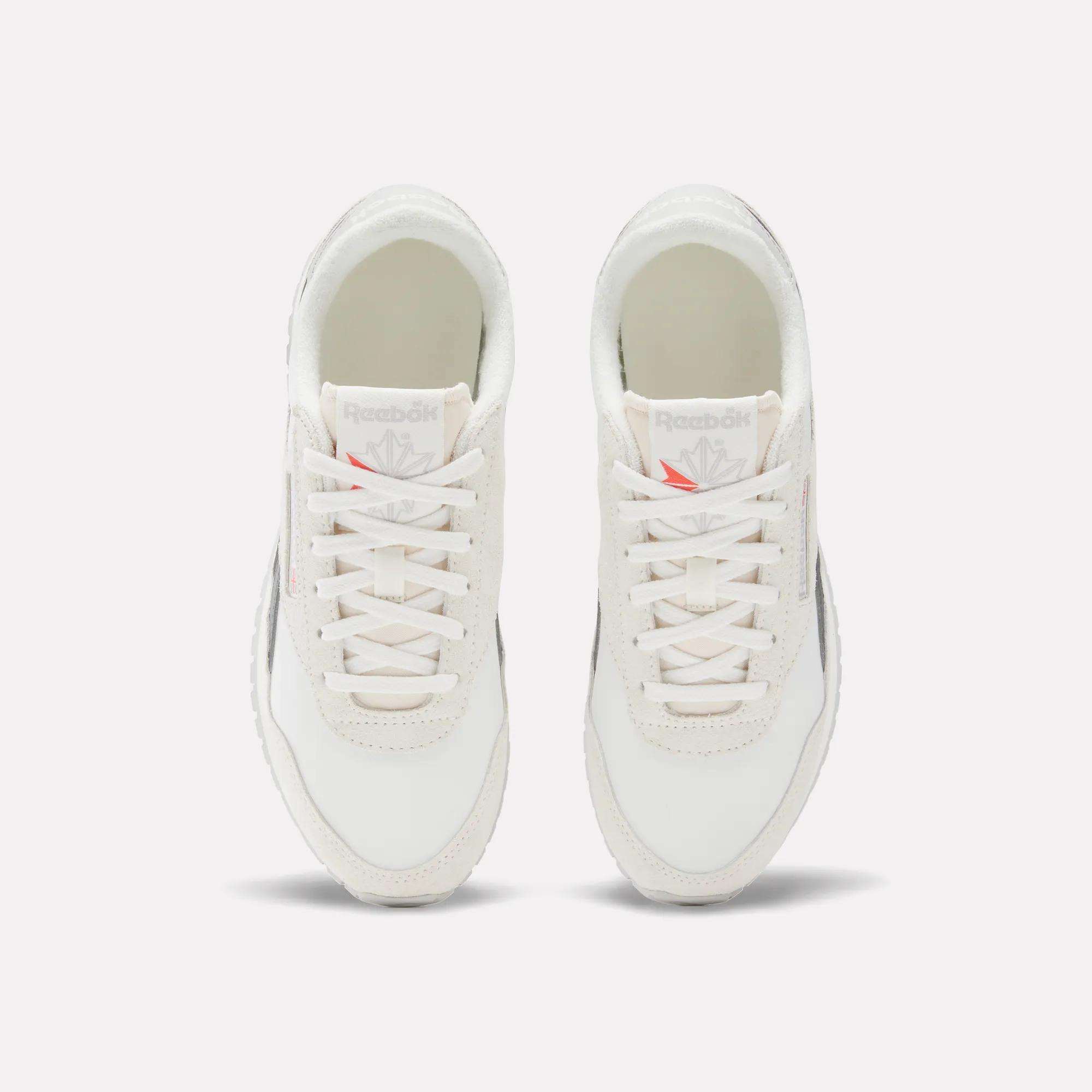 A pair of Reebok Women's Classic AZ Shoes is shown from above, featuring white laces, light grey suede accents, and Reebok logos on the tongues. The running shoes are placed side by side on a white background.