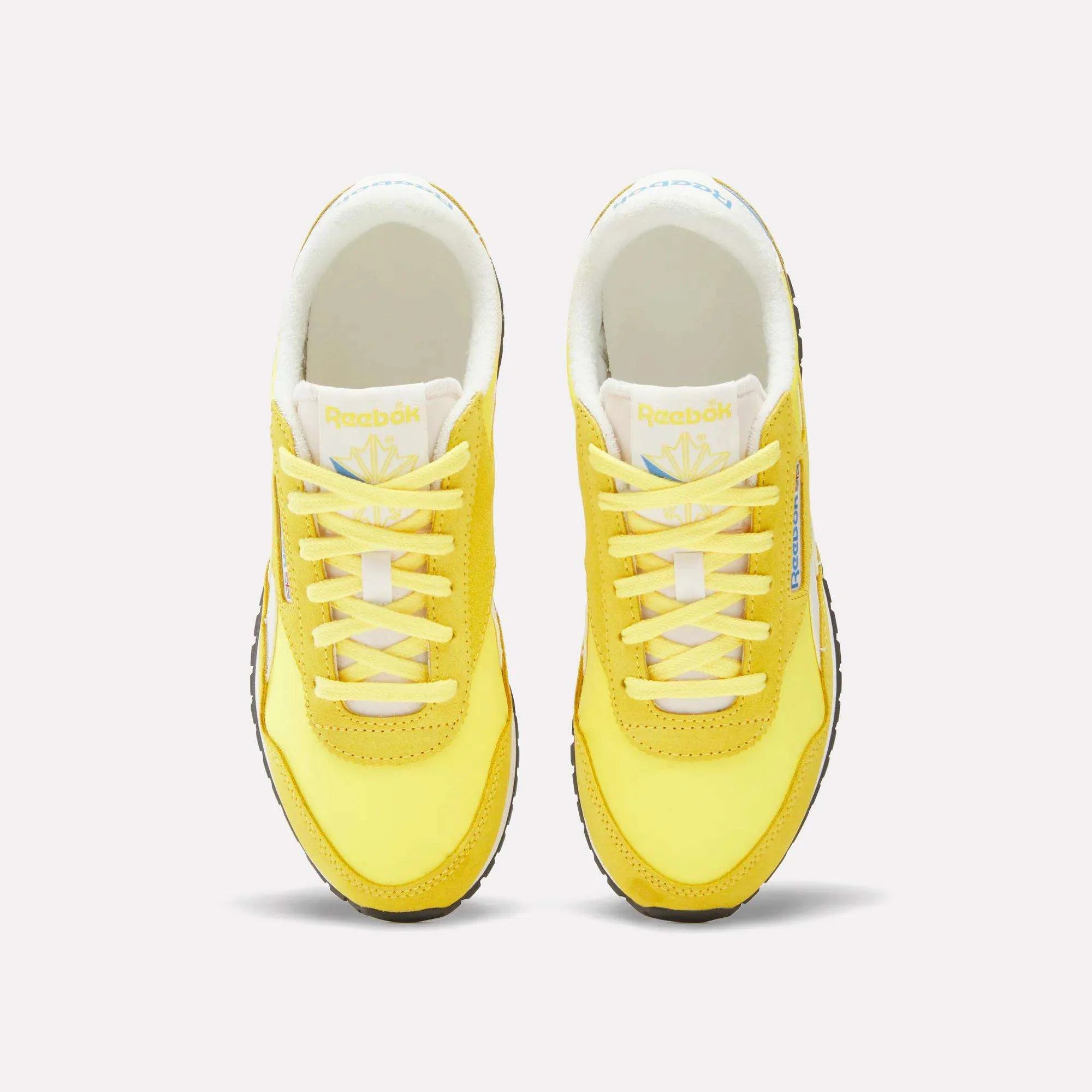 A pair of yellow Reebok sneakers with white laces and soles, shown from a top-down view against a plain white background.