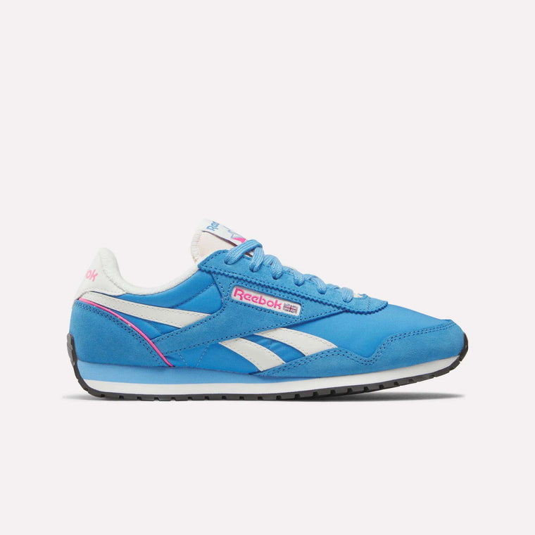 The Reebok Women's Classic AZ Shoes feature a blue design with white and pink accents, Reebok logos on the side and heel, a white sole, and blue laces for retro running style on a plain white background.