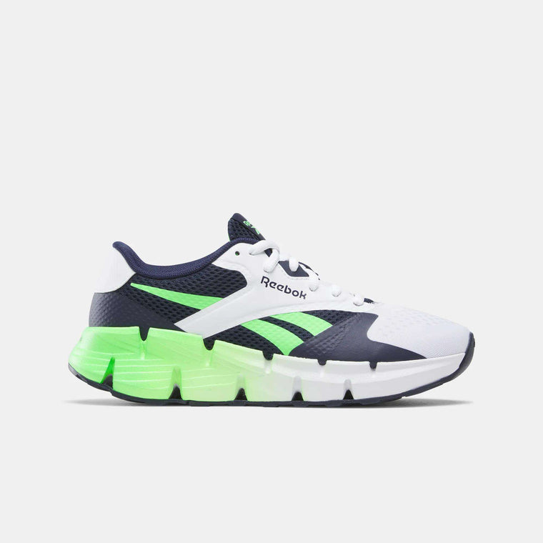 The Reebok Zig Dynamica 5 Shoes for big kids feature a white mesh upper with navy and neon green accents, a chunky segmented sole with a bright green gradient, and Floatride FuelFoam cushioning for comfort. The Reebok logo appears on the side.